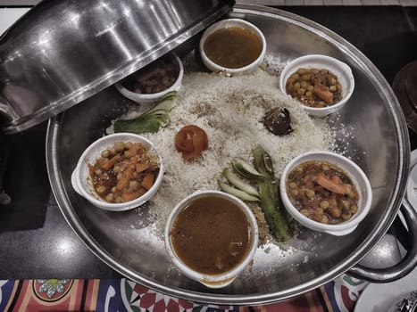 Various vegetables and meat with curry sauce in a frying pan along with rice on the table in a restaurant. View from above.