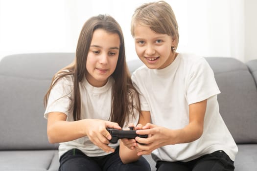 Two little girlfriends playing video game with joysticks. Excited and focused european children. Childhood concept. Entertainment and leisure. Idea of friendship. Grey background in studio. Copy space. High quality photo