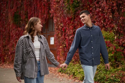 Young Cute Female Hugs Boyfriend. In Autumn Outdoor. Lovers Walking in Park. Attractive Funny Couple. Lovestory in Forest. Man and Woman. Cute Lovers in the Park. Family Concept. Happy Couple.