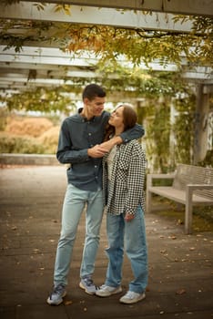 Young Cute Female Hugs Boyfriend. In Autumn Outdoor. Lovers Walking in Park. Attractive Funny Couple. Lovestory in Forest. Man and Woman. Cute Lovers in the Park. Family Concept. Happy Couple.