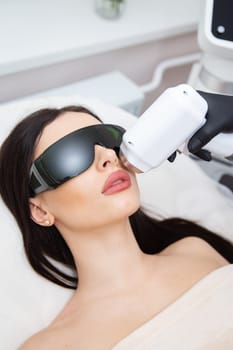 The process of laser hair removal of the female body. professional cosmetology, epilation of the face and upper lip area. Girl in goggles. Body care concept