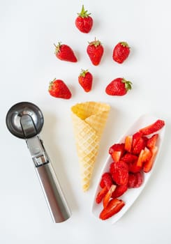 The image features fresh strawberries, a waffle cone, an ice cream scoop, and sliced strawberries on a white plate, isolated on a white background