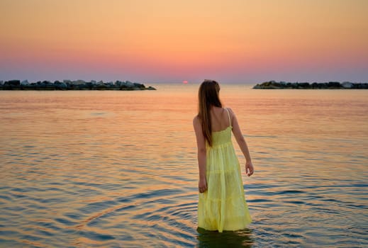 girl walking in the sea enjoying the sunrise, concept of summer holiday and health