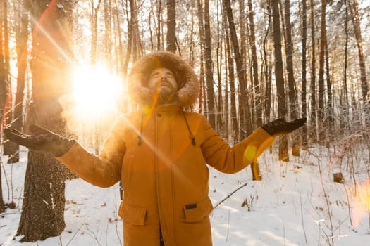 Happy bearded man in hat throws up snow in winter nature. Snowy cold season and holidays lifestyle