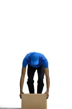 A male deliveryman, on a white background, in full height, put down a box.
