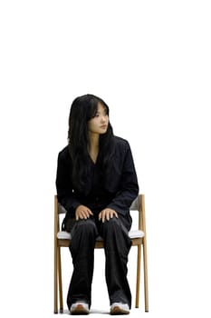 A woman in black clothes, on a white background, is sitting on a chair.