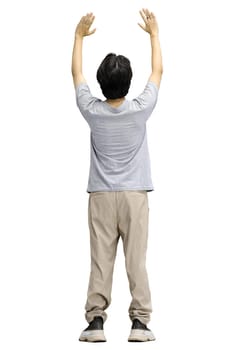 A guy in a gray T-shirt, on a white background, in full height, raised his hands up.