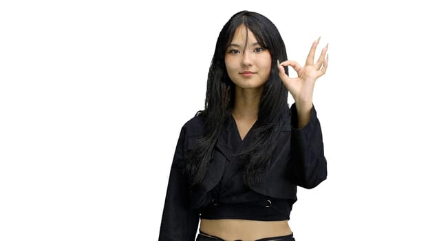 A girl in black clothes, on a white background, close-up, shows an ok sign.