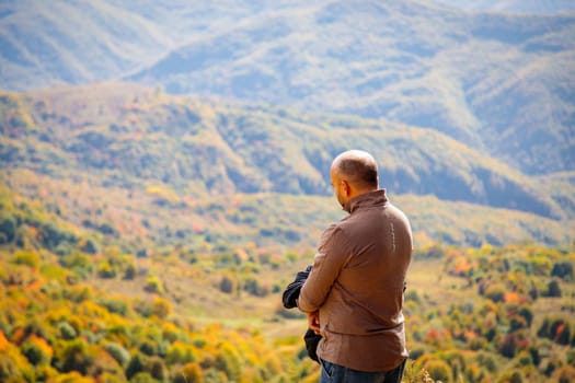 A man is captivated by the majestic mountain landscape from a sacred viewpoint. The tranquil scene exudes a sense of peace and serenity, inviting viewers to immerse themselves in the beauty of nature.
