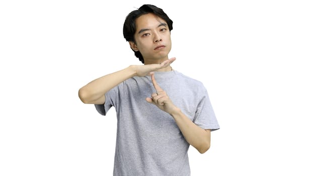 A guy in a gray T-shirt, on a white background, close-up, shows a pause sign.