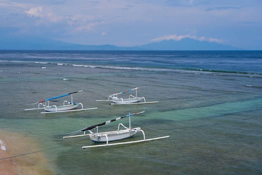Traditional local colored fisherman's catamaran boats on the ocean shore on an island in Indonesia