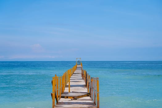 The old wooden pier goes into the horizon of the incredible azure color of the ocean
