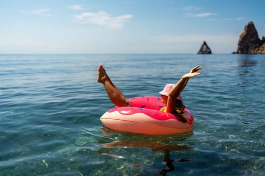 Summer vacation woman in hat floats on an inflatable donut mattress. Happy woman relaxing and enjoying family summer travel holidays travel on the sea