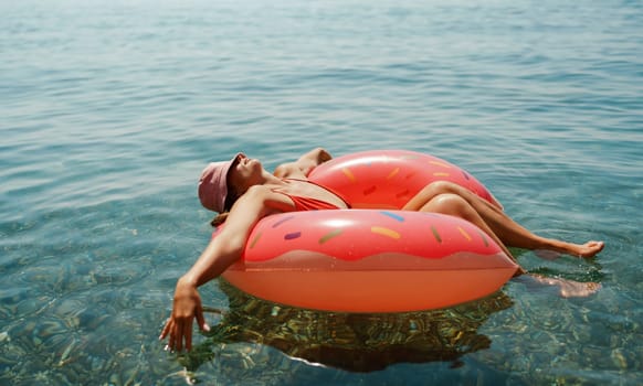 Summer vacation woman in hat floats on an inflatable donut mattress. Happy woman relaxing and enjoying family summer travel holidays travel on the sea