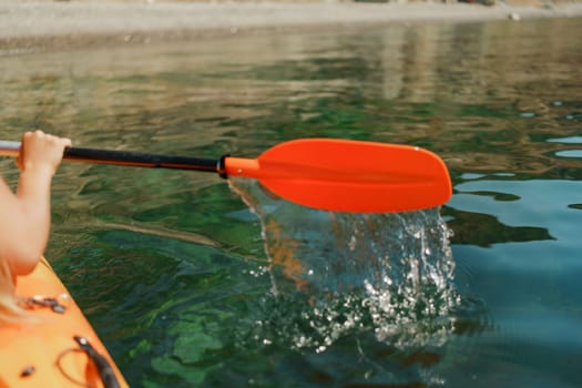 Kayak paddle sea vacation. Person paddles with orange paddle oar on kayak in sea. Leisure active lifestyle recreation activity rest tourism travel.