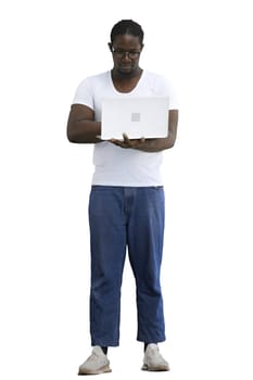 Full-length man in a white T-shirt typing on a laptop on a White background.