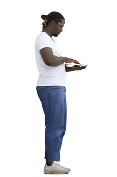 Full-length man in a white T-shirt typing on a laptop on a White background, in profile.