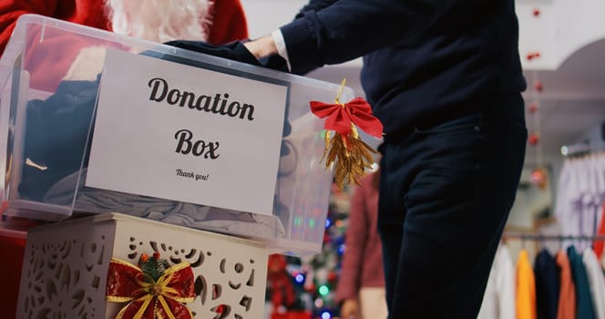 Close up shot of charity box in xmas ornate clothing store. Caring community touched by Christmas spirit donating clothes for philantropy efforts during festive holiday season