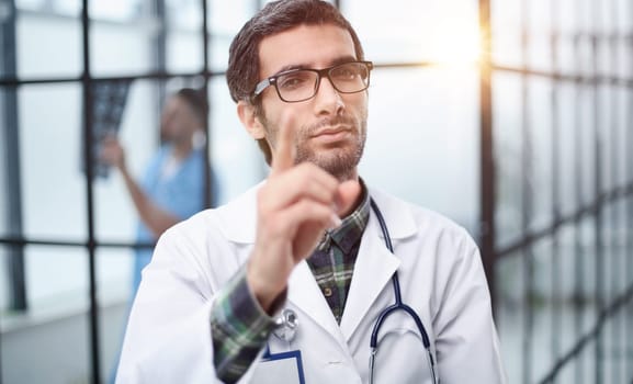 attentive doctor in a white coat pointing his finger at you while standing in the corridor of the hospital