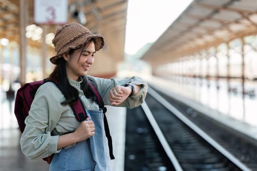 Young woman looking at smart watch with backpack. Young woman waiting for train.