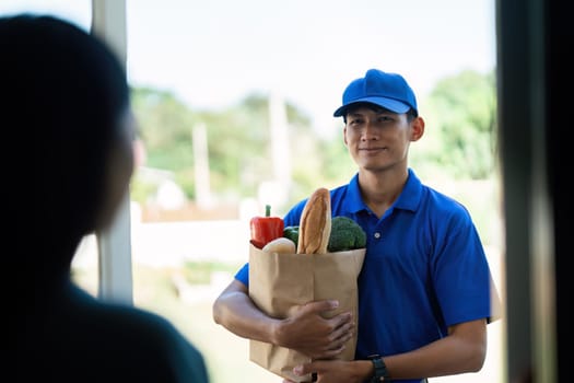 Asian young delivery man delivering package to female customer at home.