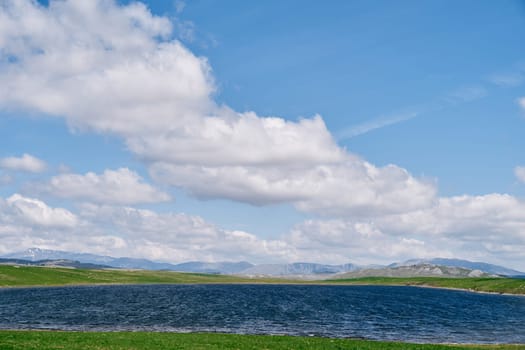 Blue surface of Lake Vrazje in a green valley against the background of a cloudy sky. Montenegro. High quality photo