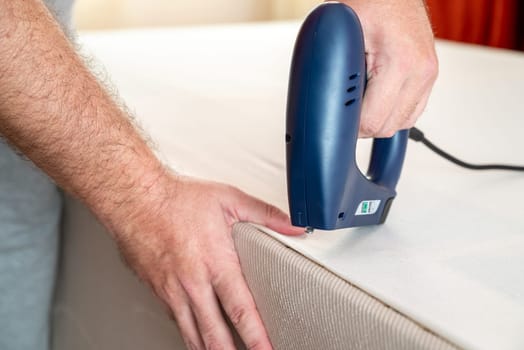 Worker stapling sofa lining with electric staple gun