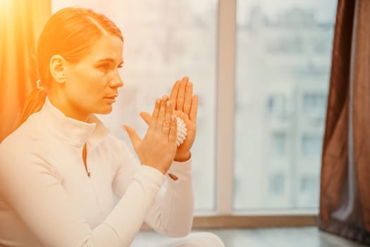 Athletic slim caucasian woman doing thigh self-massage with a massage ball indoors. Self-isolating massage.