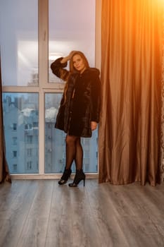 Young beautiful glamorous woman in a black luxurious fur coat posing against the background of a golden wall. fashion portrait.