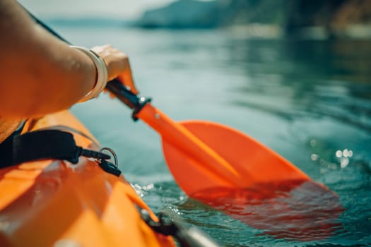 Kayak paddle sea vacation. Person paddles with orange paddle oar on kayak in sea. Leisure active lifestyle recreation activity rest tourism travel.