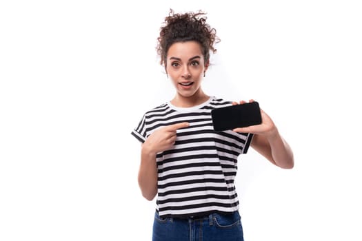 young caucasian woman with a curly haircut dressed in a striped summer t-shirt shows the smartphone screen.