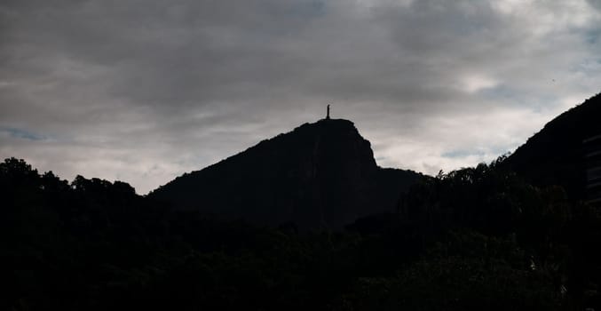 Silhouetted Christ the Redeemer statue against a dramatic evening sky in Rio de Janeiro.