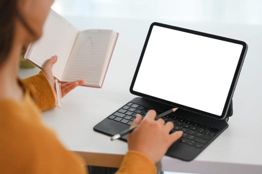 Cropped shot young businesswoman holding notepad and working on digital tablet