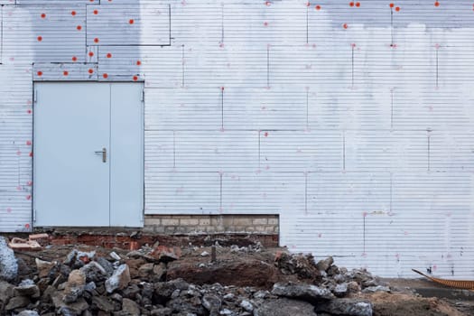 Large metal door on a new built wall and construction waste