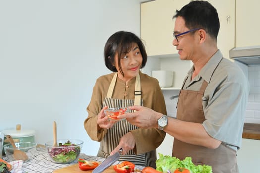 Cheerful middle age couple cooking a healthy meal at kitchen. Healthy lifestyle and nutrition concept