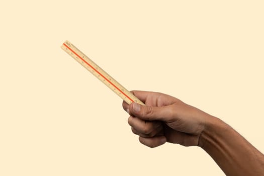 Black male hand holding a measuring ruler on light yellow isolated. High quality photo