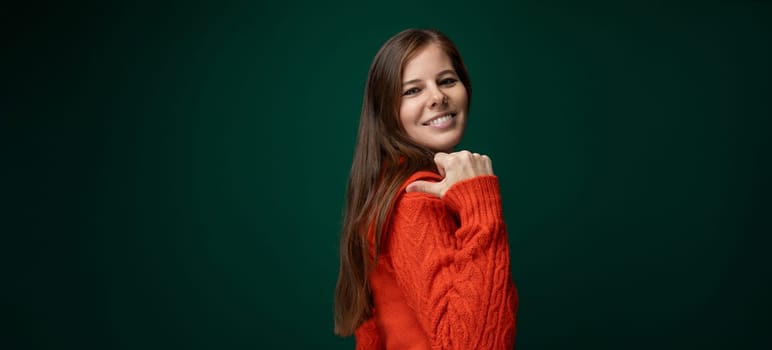 Cheerful 30 year old woman with brown hair points with her hand to the news.