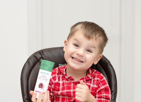 Dnepr, Ukraine - January 03,2024: a small handsome boy is sitting at a table with products from the cosmetic company LR Health and Beauty, vitamins, probiotic, colostrum. Close-up