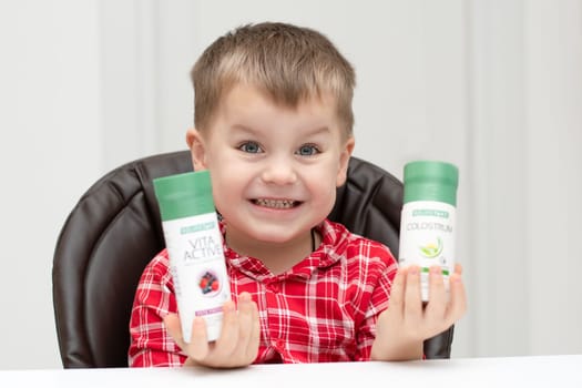 Dnepr, Ukraine - January 03,2024: a small handsome boy is sitting at a table with products from the cosmetic company LR Health and Beauty, vitamins, probiotic, colostrum. Close-up