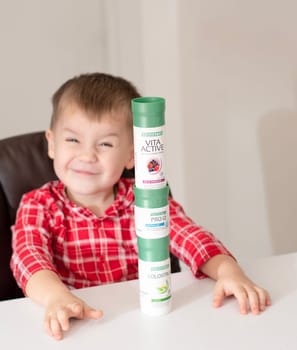 Dnepr, Ukraine - January 03,2024: a small handsome boy is sitting at a table with products from the cosmetic company LR Health and Beauty, vitamins, probiotic, colostrum. Close-up