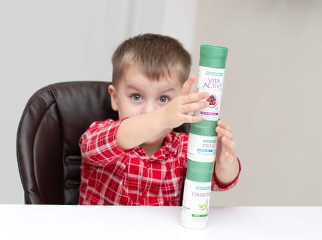 Dnepr, Ukraine - January 03,2024: a small handsome boy is sitting at a table with products from the cosmetic company LR Health and Beauty, vitamins, probiotic, colostrum. Close-up