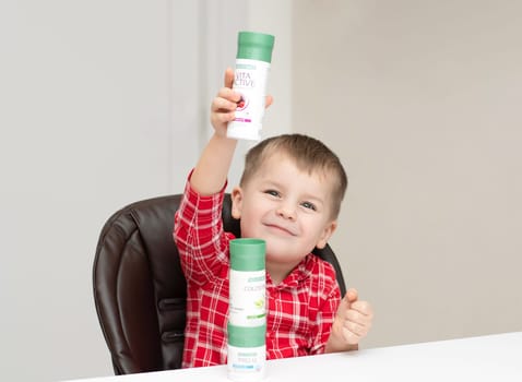 Dnepr, Ukraine - January 03,2024: a small handsome boy is sitting at a table with products from the cosmetic company LR Health and Beauty, vitamins, probiotic, colostrum. Close-up