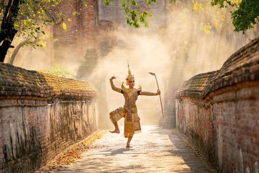 Khon or traditional Thai classic masked from the Ramakien characters as man dance in front of ancient building with tradional weapon.