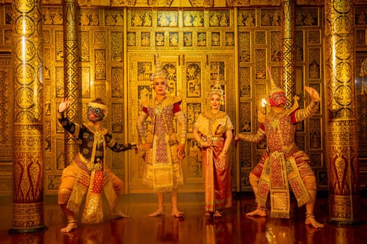 Group of Khon or traditional Thai classic masked from the Ramakien characters stand together with action of traditional dance with Thai paintings background in a public place.