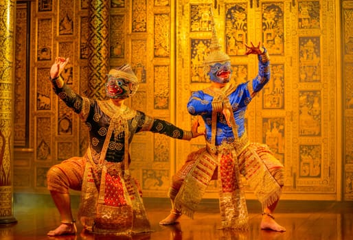 Khon or traditional Thai classic masked from the Ramakien with black and blue monkey stand together with action of traditional dance with Thai paintings background in a public place.