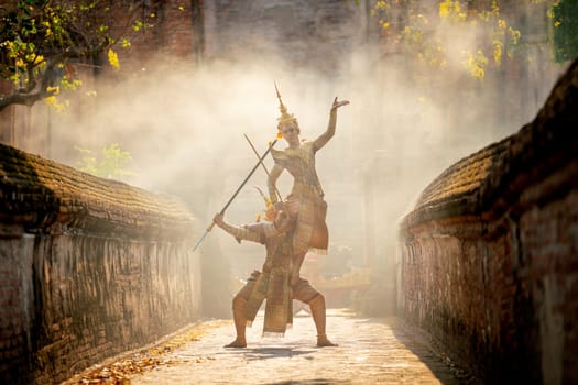 Khon or traditional Thai classic masked from the Ramakien characters action of traditional dance with fighting between human and giant with ancient building as background in public place.