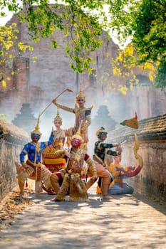 Vertical image of Small group of Khon or traditional Thai classic masked from the Ramakien characters stand together with action of traditional dance in front of Thai ancient building