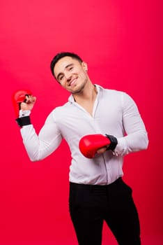 Businessman standing with boxing gloves over a red background. Looking at camera