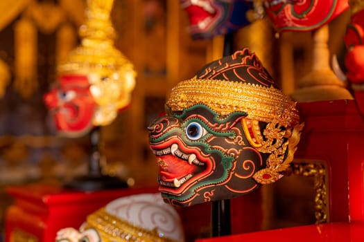 Close up of beautiful ancient traditional Thai pattern Pantomime or Khon masks are set up on wooden shelves with main focus on black monkey charactor.
