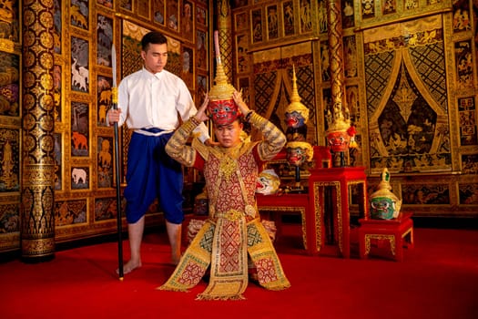 Asian man with Thai style cloth stand with man wear ancient traditional Thai pattern Pantomime also hold Khon mask in traditional ceremony of respect to teacher.